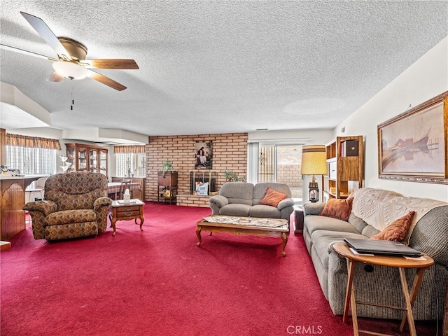 living room featuring ceiling fan, carpet flooring, a brick fireplace, and a textured ceiling