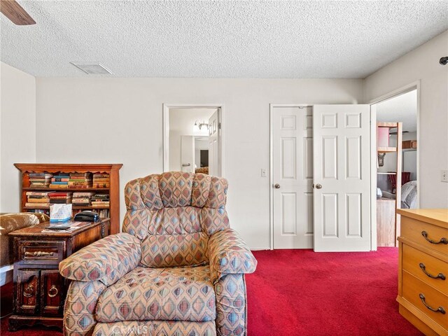 living area with a textured ceiling and dark colored carpet