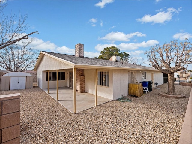 back of property with a shed and a patio