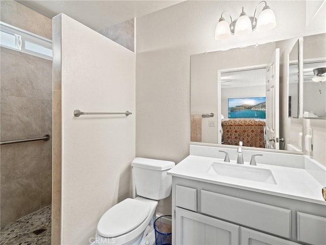 bathroom featuring tiled shower, vanity, and toilet