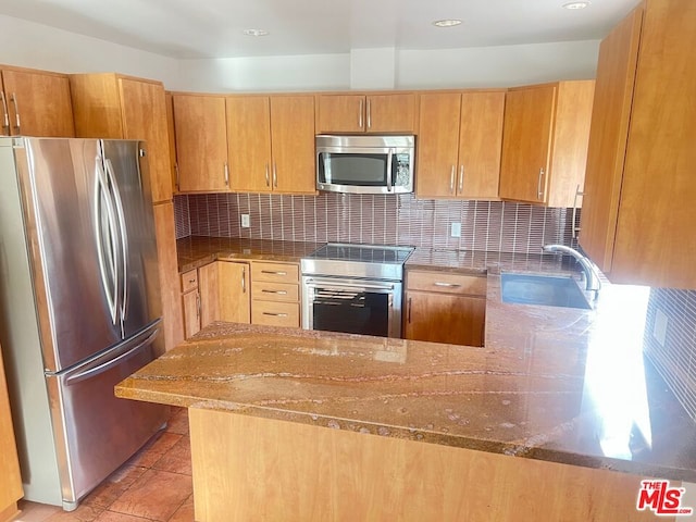 kitchen with tasteful backsplash, kitchen peninsula, and appliances with stainless steel finishes