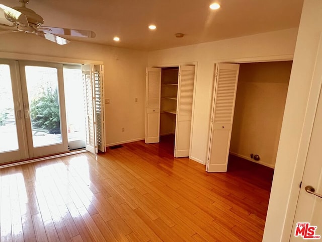 unfurnished bedroom featuring multiple closets, access to outside, and light hardwood / wood-style flooring