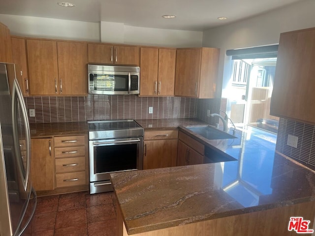 kitchen featuring sink, backsplash, stainless steel appliances, and kitchen peninsula