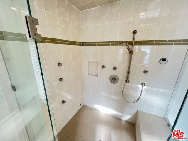 bathroom with tile walls, tile patterned flooring, and a shower with door