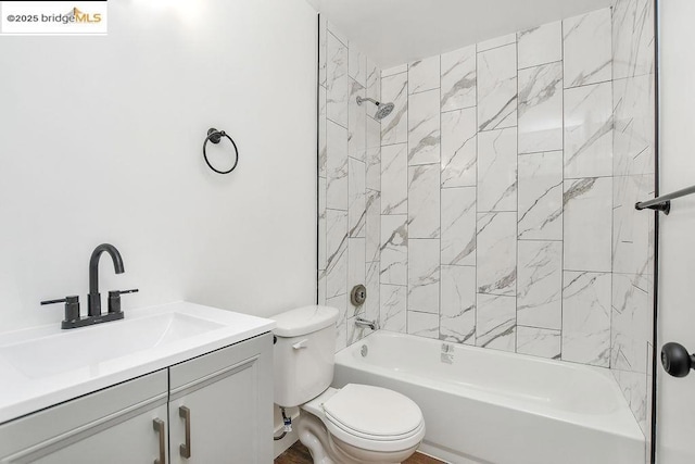 full bathroom featuring vanity, tiled shower / bath combo, and toilet