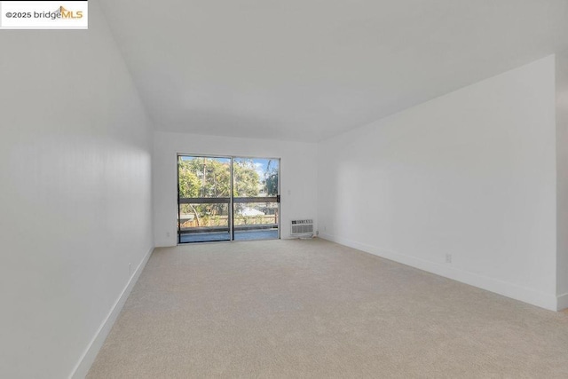 unfurnished room featuring light colored carpet and a wall mounted air conditioner