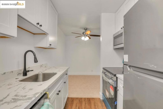 kitchen with sink, appliances with stainless steel finishes, ceiling fan, light hardwood / wood-style floors, and white cabinets