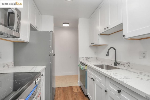 kitchen with white cabinetry, stainless steel appliances, sink, and hardwood / wood-style floors