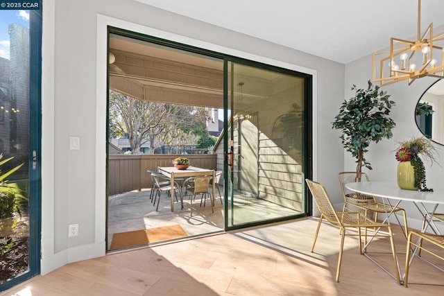 doorway with light hardwood / wood-style floors and a notable chandelier