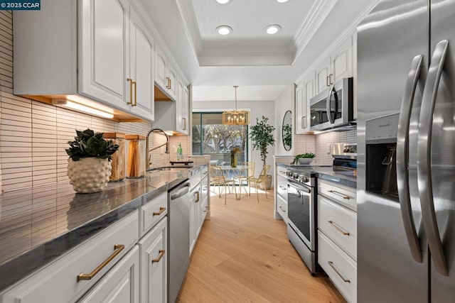 kitchen featuring hanging light fixtures, white cabinetry, appliances with stainless steel finishes, and light wood-type flooring