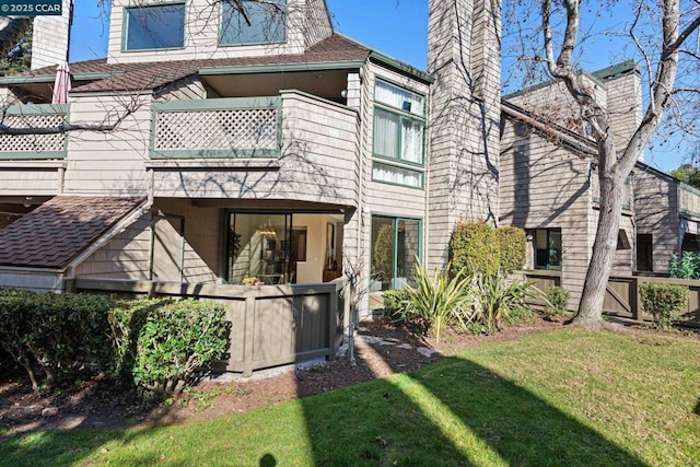 back of property with a yard and a balcony