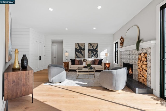 living room with wooden walls, a fireplace, and light hardwood / wood-style flooring