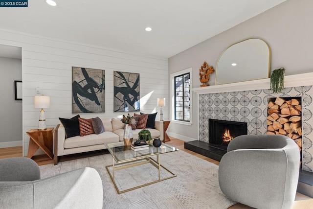 living room featuring a tiled fireplace and light hardwood / wood-style floors