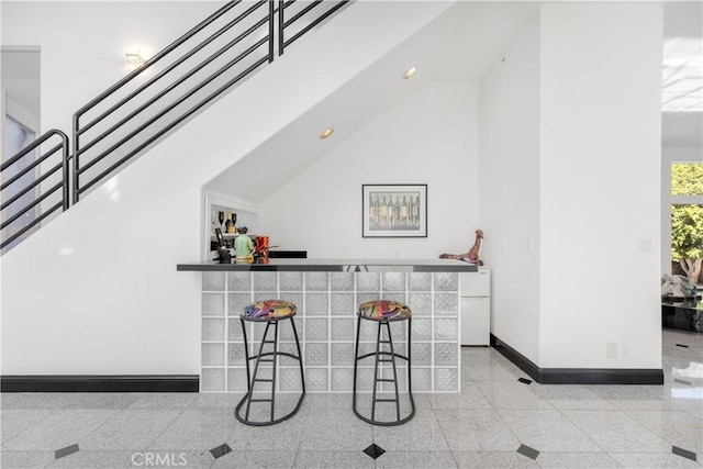 bar featuring white refrigerator and high vaulted ceiling