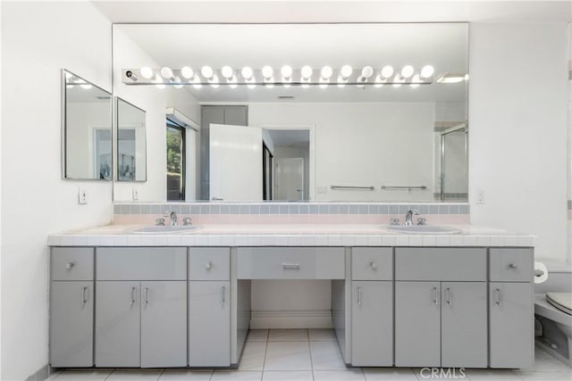 bathroom featuring walk in shower, vanity, toilet, and tile patterned flooring