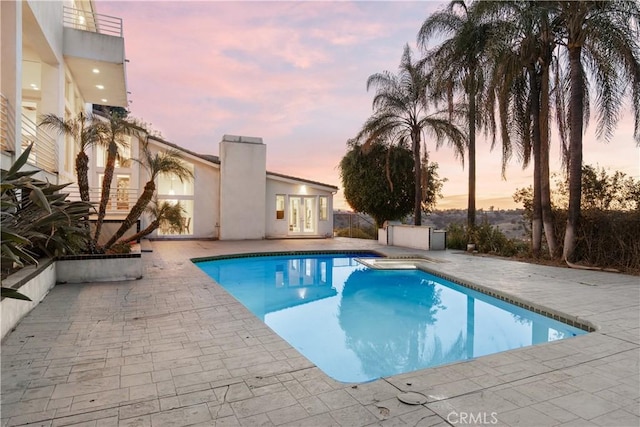 pool at dusk featuring a patio area