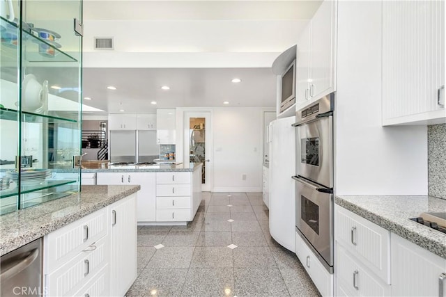 kitchen featuring white cabinetry, light stone counters, and stainless steel appliances