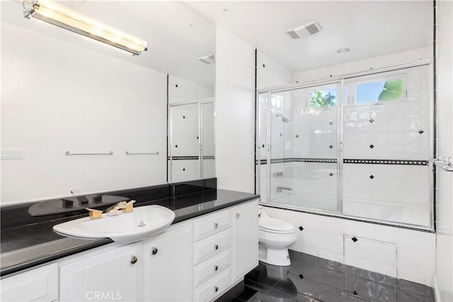 full bathroom featuring tile patterned flooring, vanity, bath / shower combo with glass door, and toilet