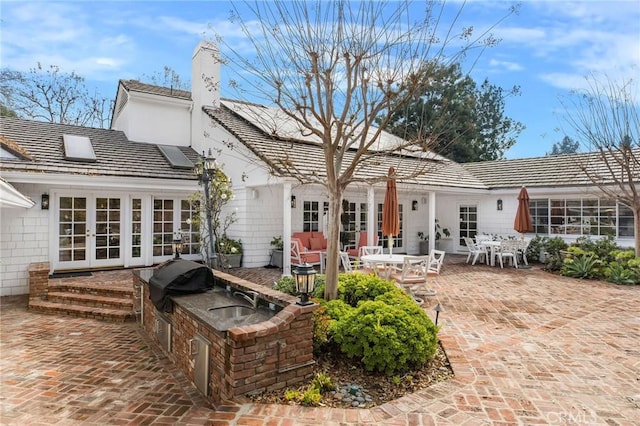 rear view of house with french doors, area for grilling, sink, and a patio