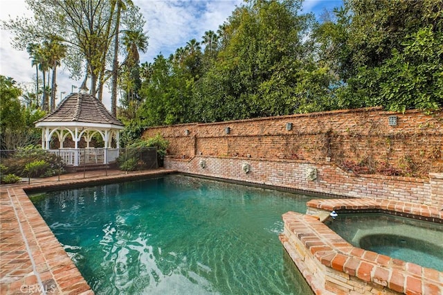 view of pool with a gazebo and an in ground hot tub