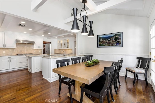 dining space featuring sink, dark wood-type flooring, and lofted ceiling with beams