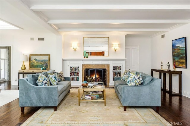 living room featuring beamed ceiling, a premium fireplace, hardwood / wood-style floors, and crown molding