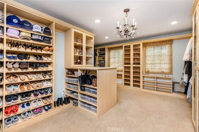 spacious closet with light colored carpet and a chandelier