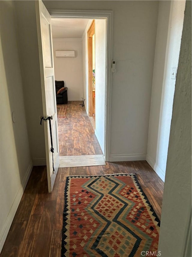 hall featuring baseboards, dark wood-style flooring, and a wall mounted air conditioner