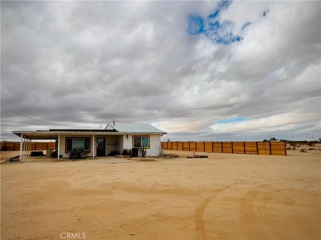 back of property featuring fence and roof mounted solar panels