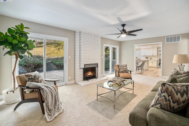 living room featuring ceiling fan, light colored carpet, and a fireplace