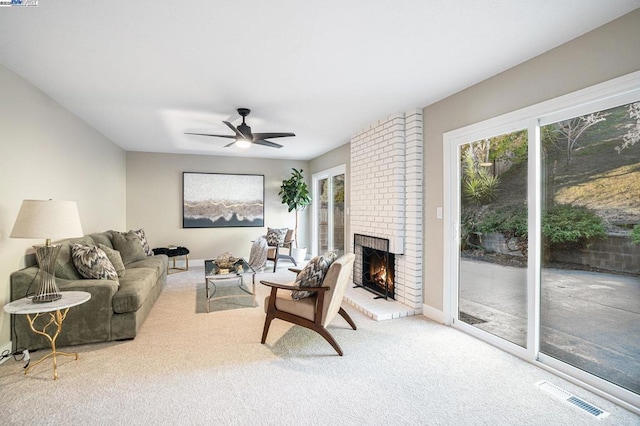 living room featuring ceiling fan, plenty of natural light, light carpet, and a fireplace