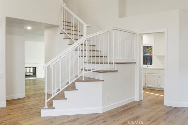 stairs with wood-type flooring and a multi sided fireplace