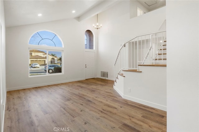 entryway with beam ceiling, wood-type flooring, and high vaulted ceiling