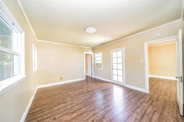 empty room with crown molding, plenty of natural light, and wood-type flooring