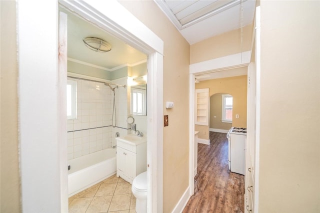 full bathroom featuring tiled shower / bath, hardwood / wood-style floors, ornamental molding, vanity, and toilet