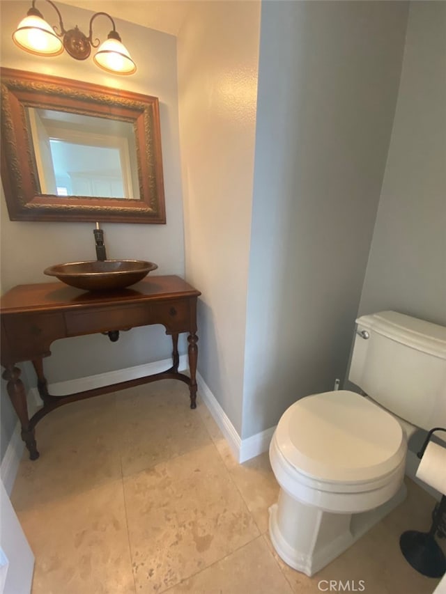 half bath featuring a sink, toilet, tile patterned flooring, and baseboards