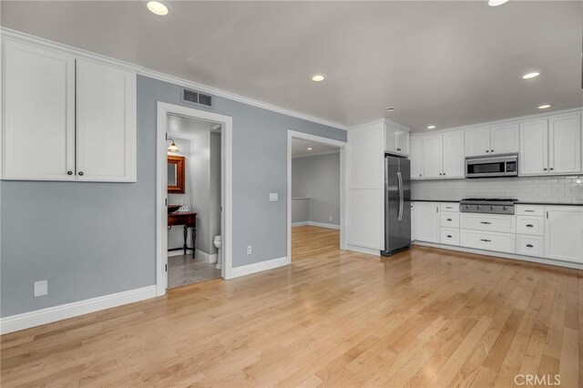 kitchen with crown molding, appliances with stainless steel finishes, backsplash, white cabinets, and light wood-type flooring