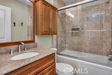 bathroom with toilet, vanity, and enclosed tub / shower combo