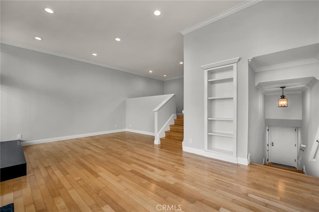 unfurnished living room featuring built in shelves, ornamental molding, and light wood-type flooring