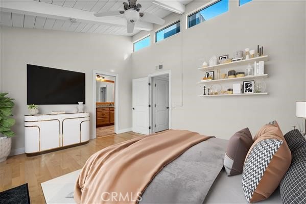 bedroom with ceiling fan, beam ceiling, light hardwood / wood-style floors, and ensuite bath