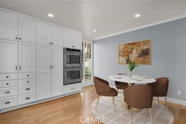 dining room with ornamental molding and light wood-type flooring