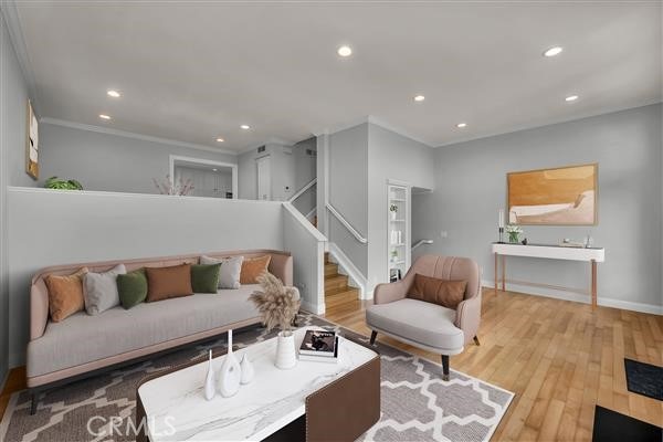 living area with recessed lighting, wood finished floors, baseboards, stairway, and crown molding