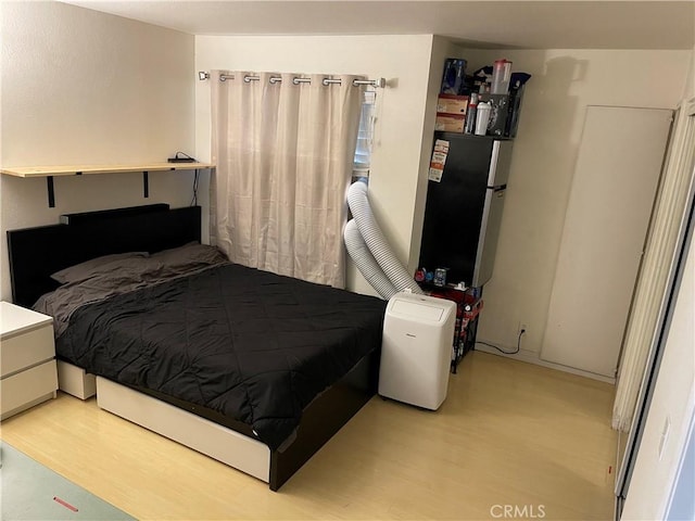 bedroom with light hardwood / wood-style flooring and stainless steel refrigerator