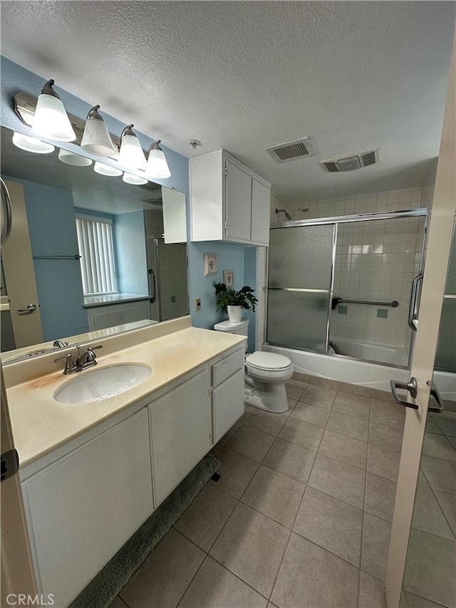 full bathroom with combined bath / shower with glass door, tile patterned flooring, vanity, toilet, and a textured ceiling