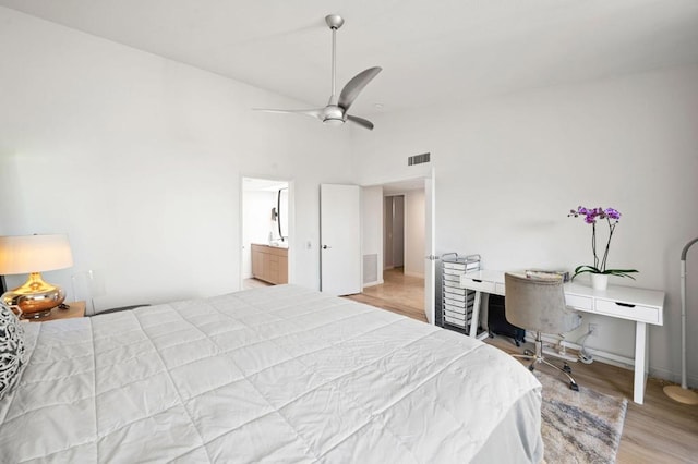 bedroom with hardwood / wood-style floors, ensuite bathroom, ceiling fan, and a high ceiling