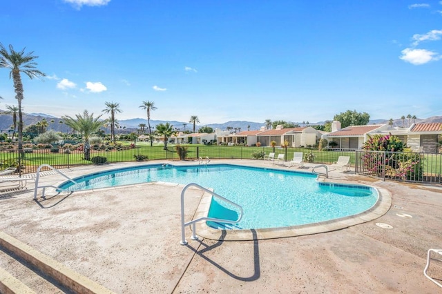 view of swimming pool featuring a mountain view, a patio area, and a lawn