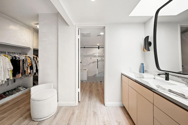 bathroom with hardwood / wood-style flooring, vanity, and an enclosed shower