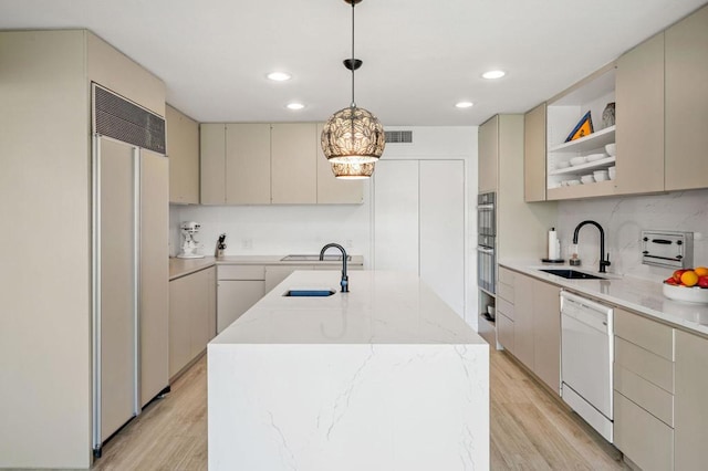 kitchen with decorative light fixtures, dishwasher, sink, paneled built in refrigerator, and a kitchen island with sink