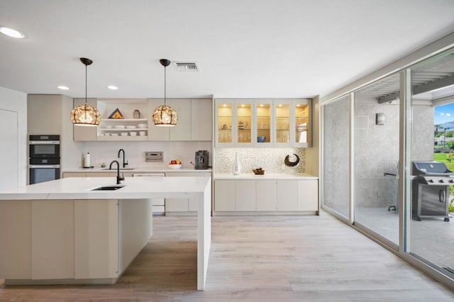 kitchen featuring pendant lighting, multiple ovens, tasteful backsplash, and expansive windows