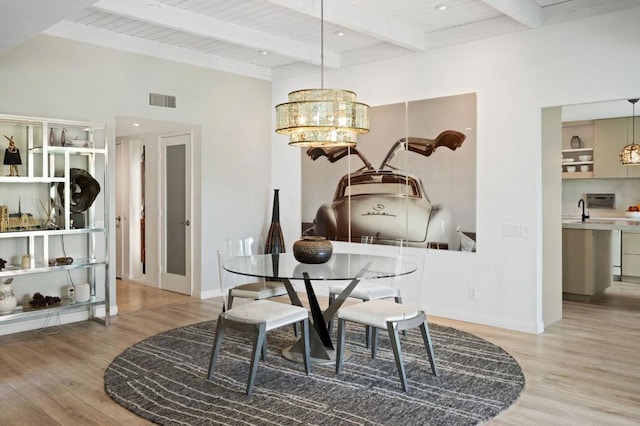 dining room featuring beam ceiling, light hardwood / wood-style floors, and wooden ceiling